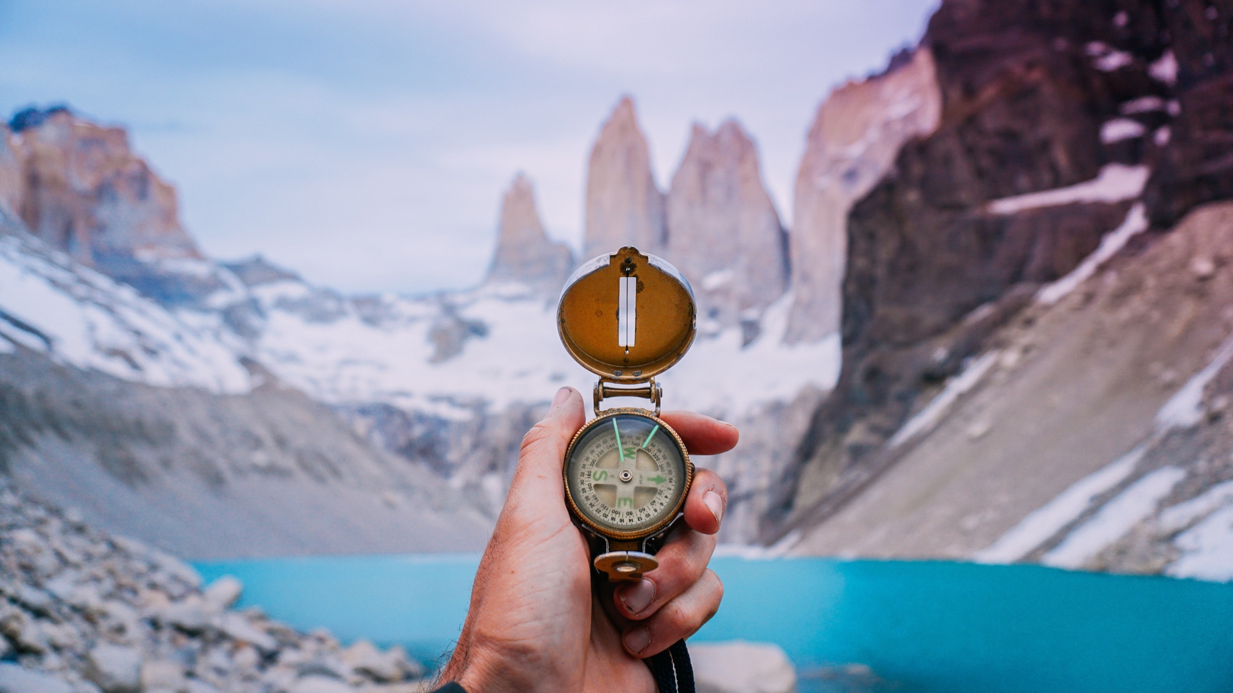 Hand mit Kompass vor einer Berglandschaft als Sinnbild für Orientierung